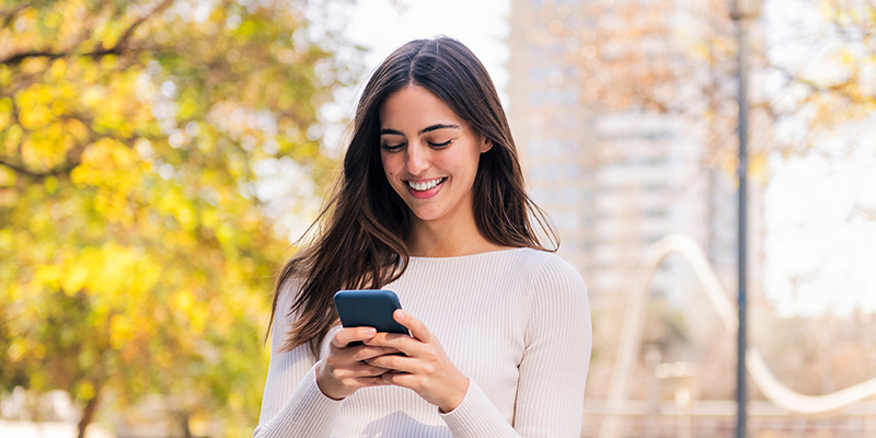 Woman smiling while looking at her cell phone.