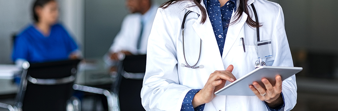 Medical professional wearing stethoscope and holding tablet